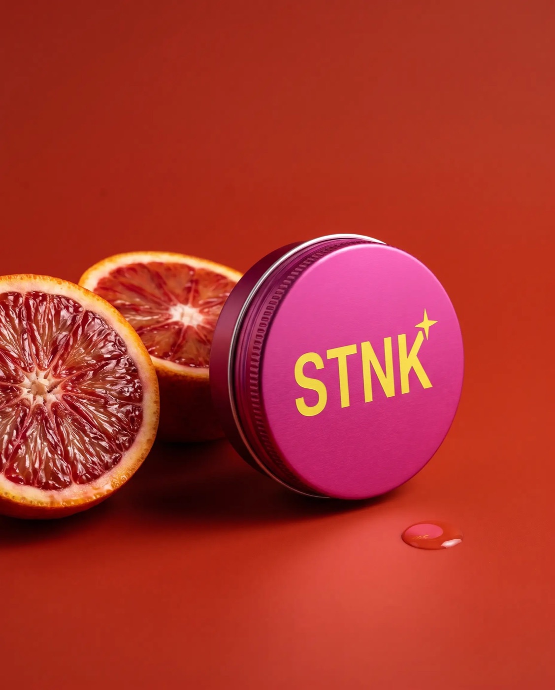 The magenta Blood Orange STNK tin beside a cut blood orange