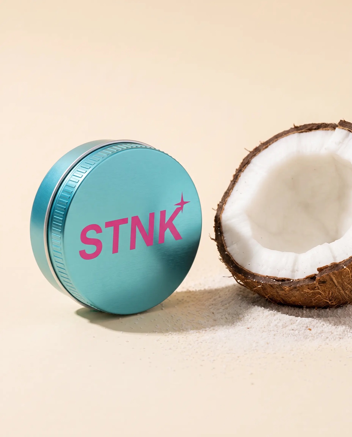 The teal Coastal Coconut STNK tin beside a cracked coconut